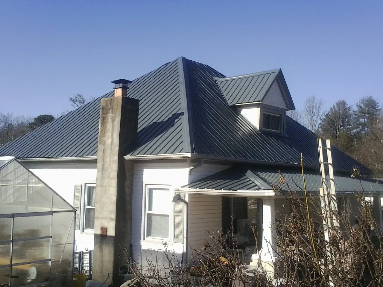 Dark blue standing seam metal roof on a white farmhouse with dormer — Slate & Tile Roof Repair by Roofing Brothers in Tonopah